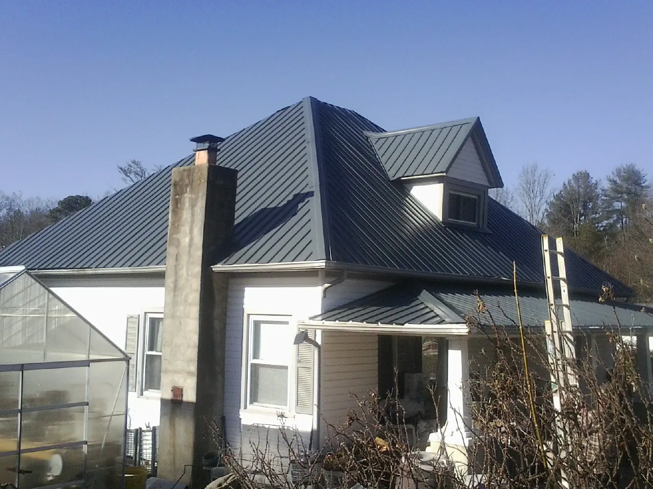 Dark blue standing seam metal roof on a white farmhouse with dormer — Slate & Tile Roof Repair by Roofing Brothers in Kings Bay