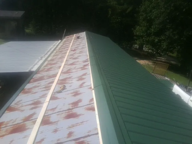 Old rusted panels beside newly installed green metal roofing — Wind Damage Roof Repair by Roofing Brothers in Kings Bay