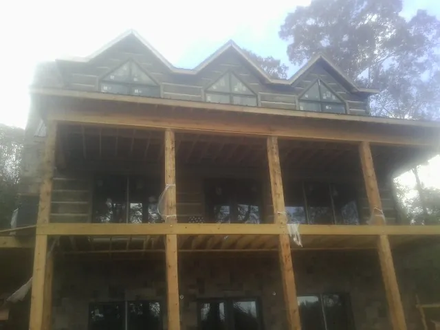 Dormers and porch framing on a large log home under construction — Roof Coating work by our crew in Kings Bay