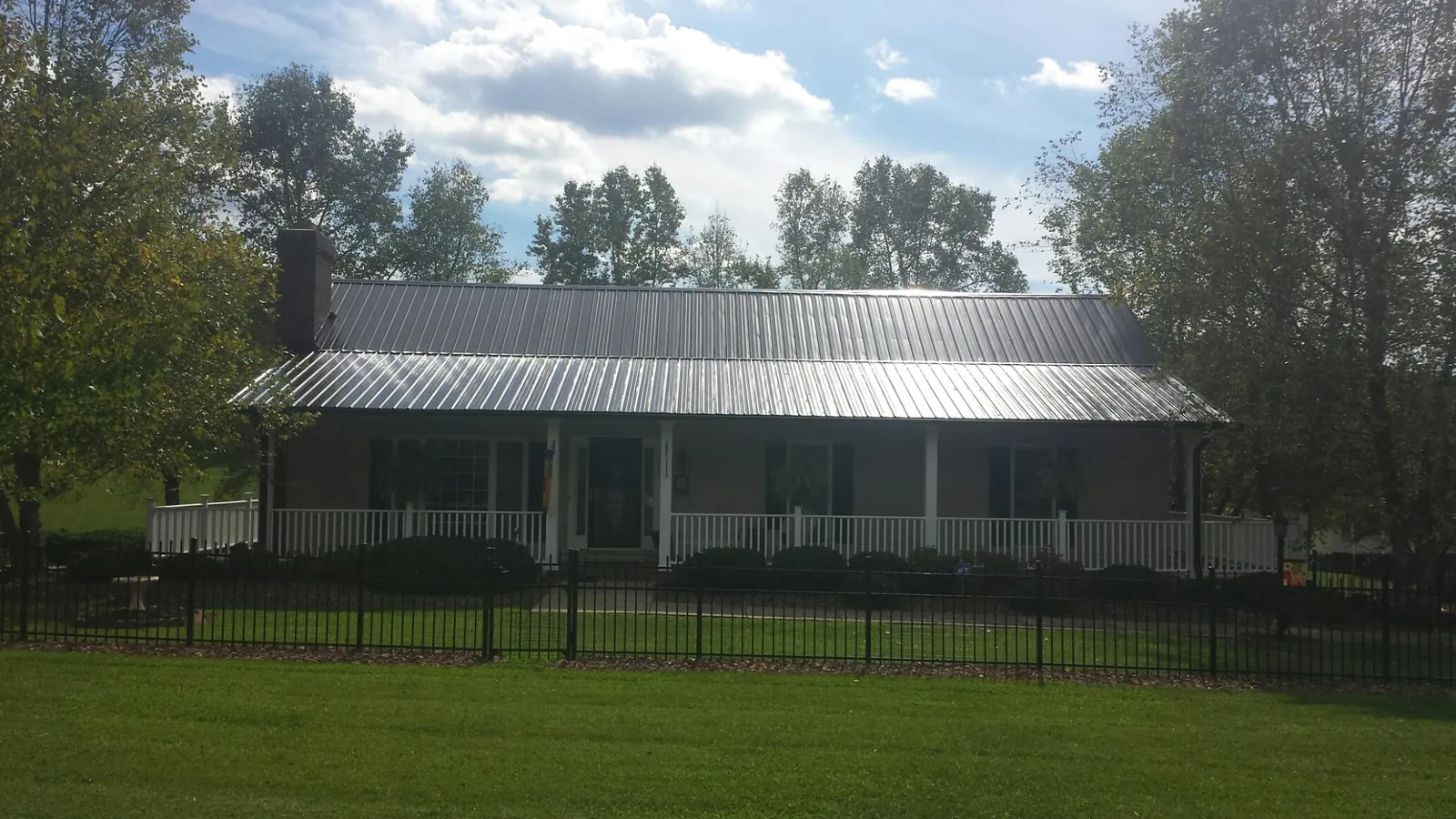 Gray metal roof on a brick ranch with a full width front porch — Gutter Guard Installation work by our crew in Kings Bay
