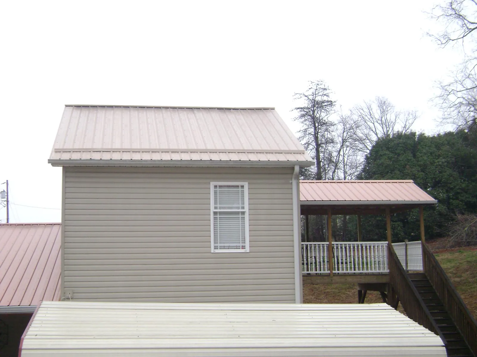 Tan metal roofs on a two story addition and attached porch, from a Roof Replacement job in Kings Bay