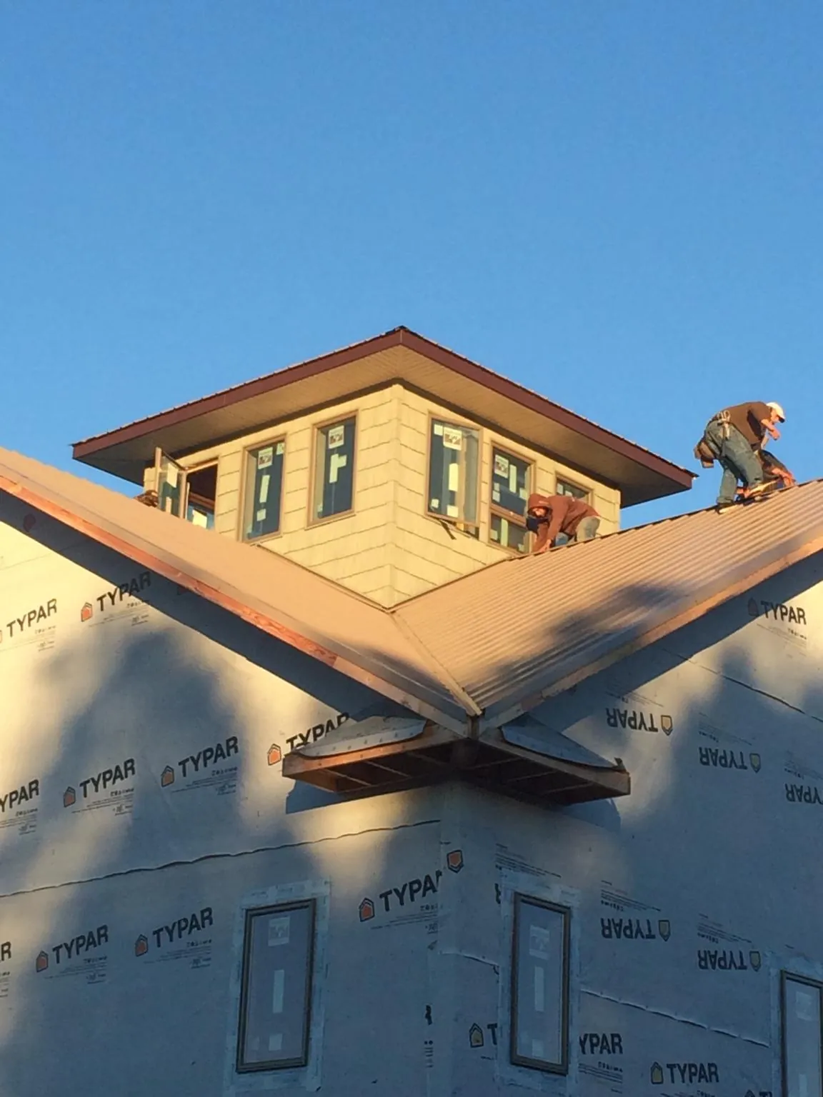 Roofers working around a rooftop cupola on a new metal roof at sunset — Roof Waterproofing in Kings Bay by Roofing Brothers